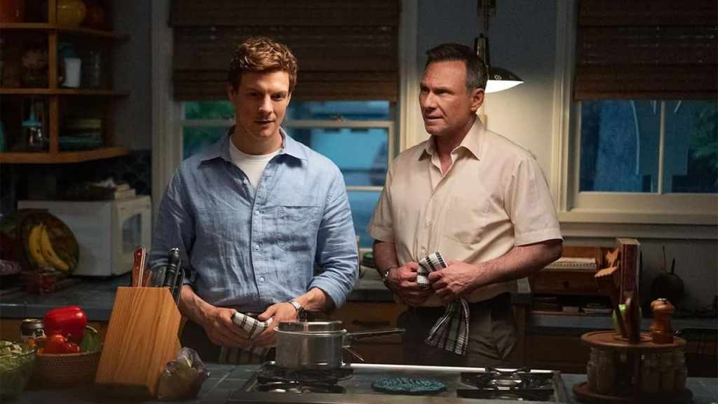 A promotional still from TV series Dexter: Original Sin featuring Patrick Gibson as young Dexter Morgan, and Christian Slater as Harry Morgan in a kitchen, each holding a towel.