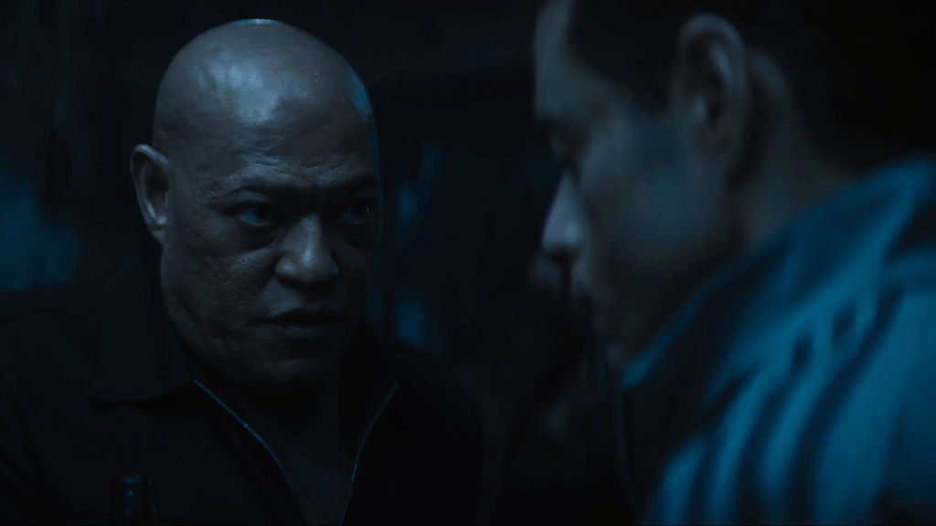 Promotional still from The Amateur (2025) movie, featuring Laurence Fishburne as Henderson facing Rami Malek as Charlie Heller in a dark alley.