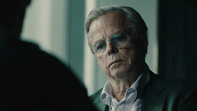 A still image from Agent Hamilton Season 2 featuring a smartly dressed older man facing a silhouetted person in the foreground. 