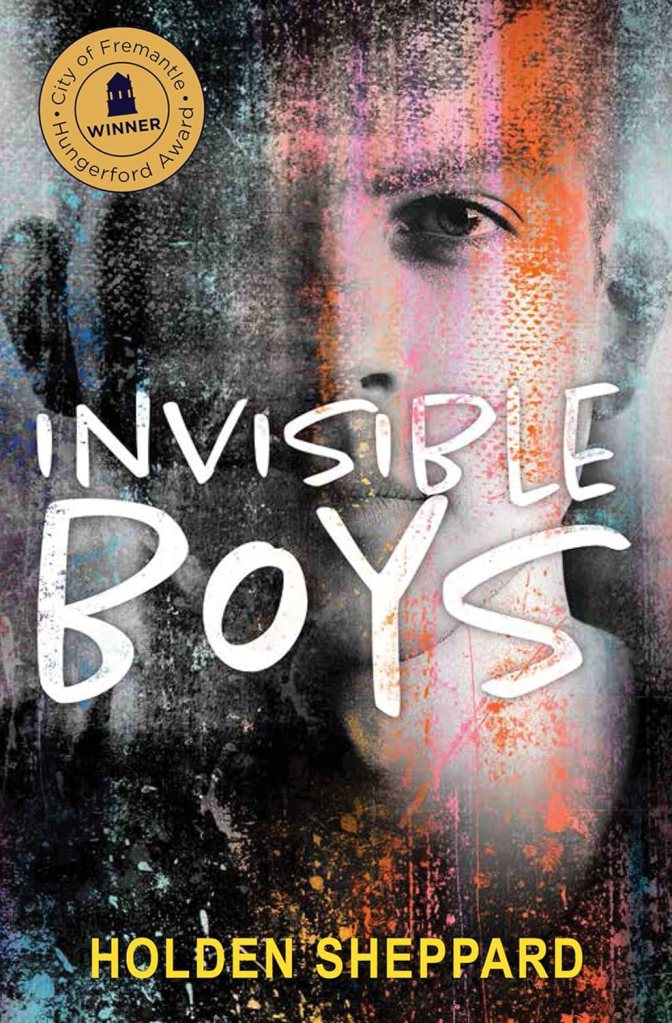 Book cover of Invisible Boys by Holden Sheppard, featuring a partial face of a young man blending into a grungy, multicolored textured background. The title 'INVISIBLE BOYS' is written in bold, white hand-lettered font across the center, and the author’s name appears at the bottom in yellow capital letters. A gold award badge in the top-left corner reads 'City of Fremantle Hungerford Award – WINNER.'