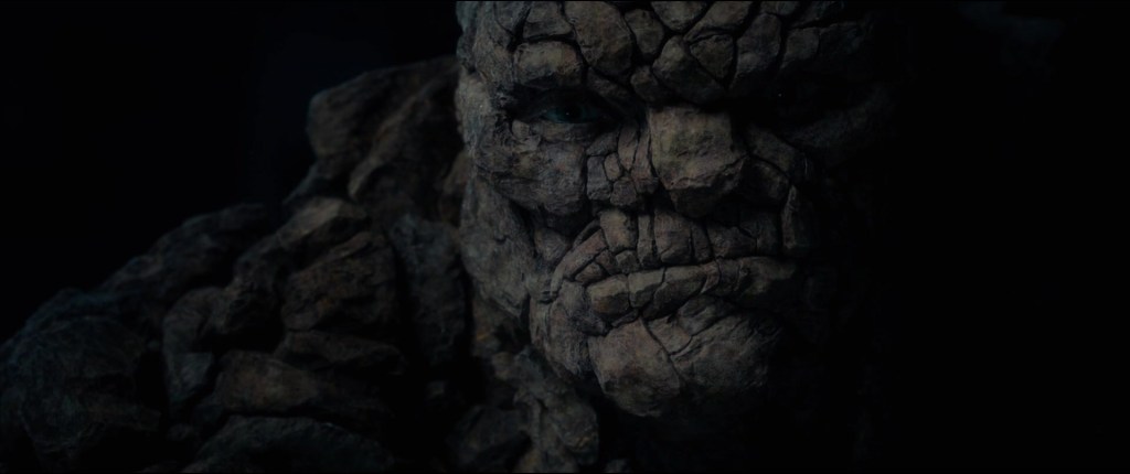 A still from 2015's Fantastic Four movie featuring Ben Grim's rocky face in a shadowy.