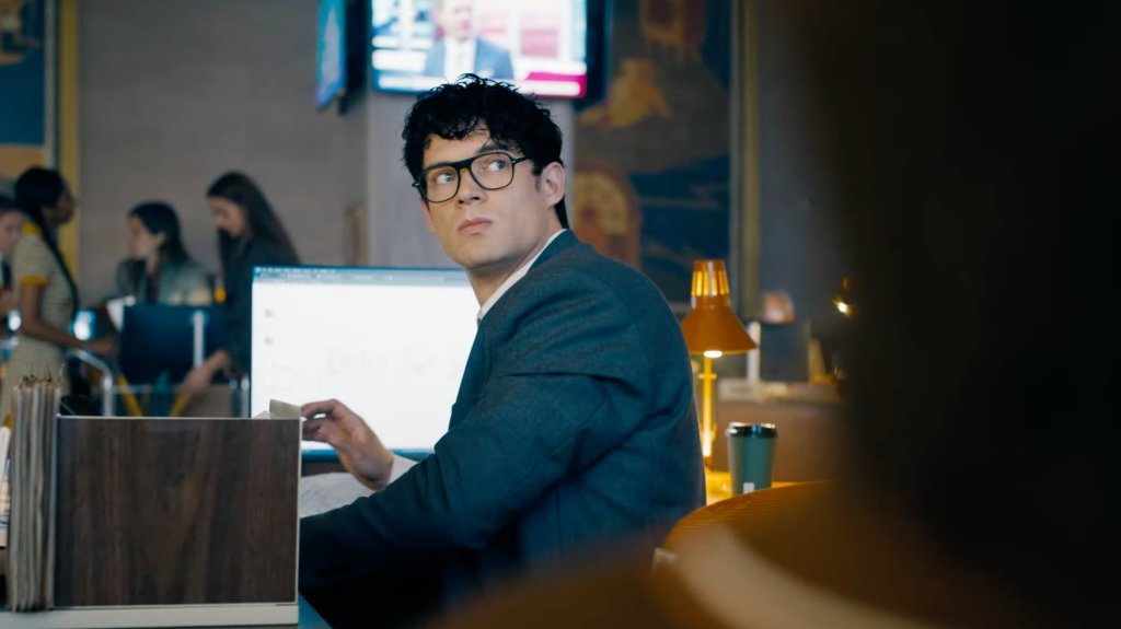 David Corenswet as Karl Kent wearing a suit and glasses, sat at his desk in the 2025 Superman movie.