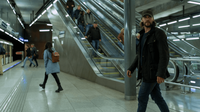 Taylor Kitsch in The Terminal List: Dark Wolf (2025), wearing a cap, dark clothes on the platform of a metro station.