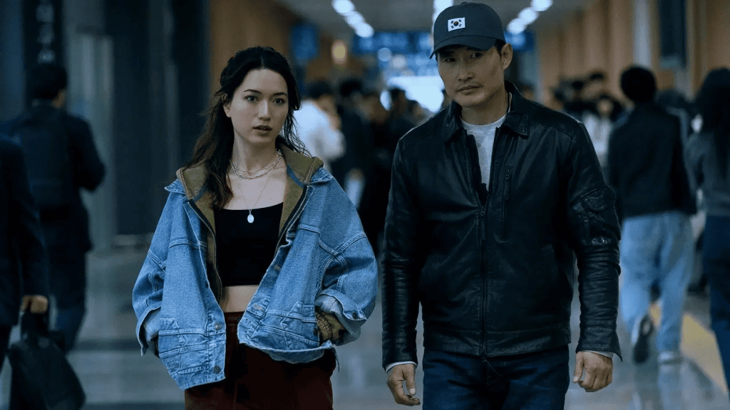 A young woman walks beside an older man wearing a cap in a crowded train station, a scene from the tv series Butterfly.