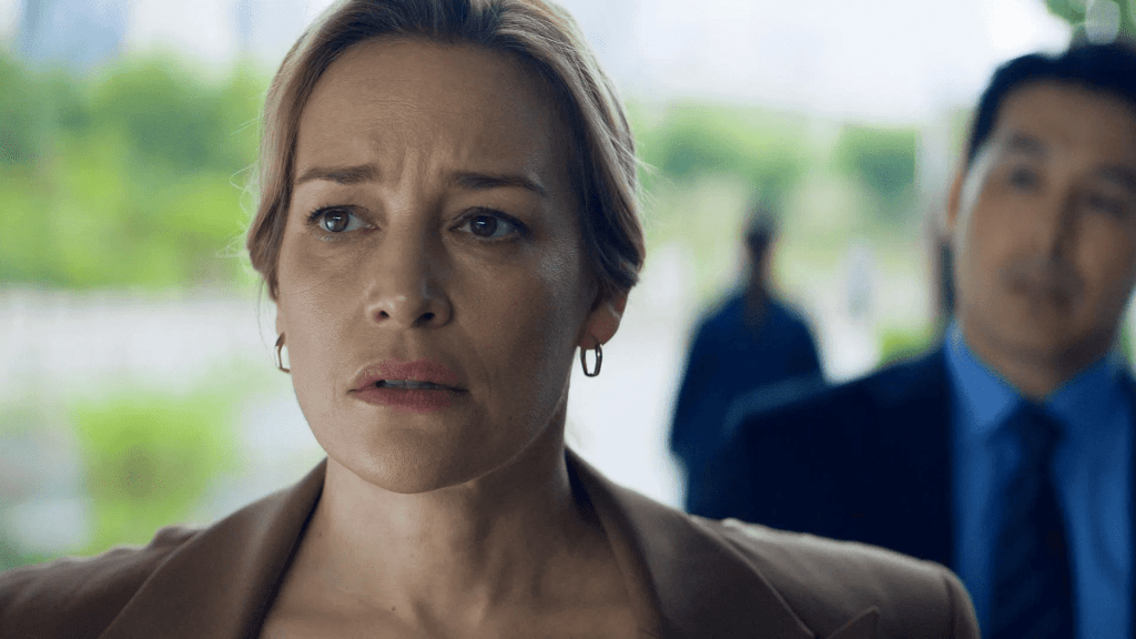 Close-up of a woman looking tense and uneasy, with a blurred man in the background, in a dramatic scene from Butterfly.