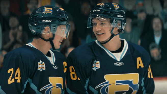 Two rival hockey players smile at each other, showcasing camaraderie on the ice.