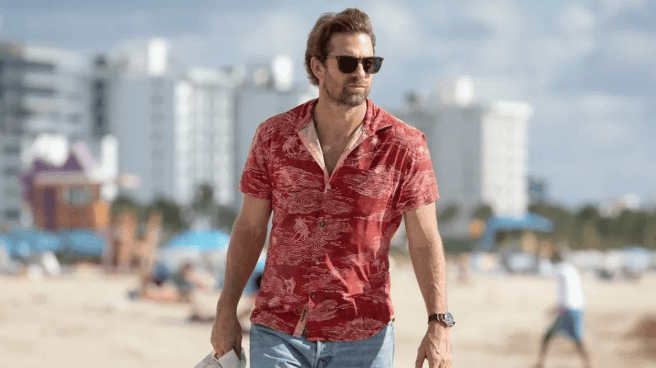 Scott Speedman as RJ Decker wearing sunglasses walking on a beach