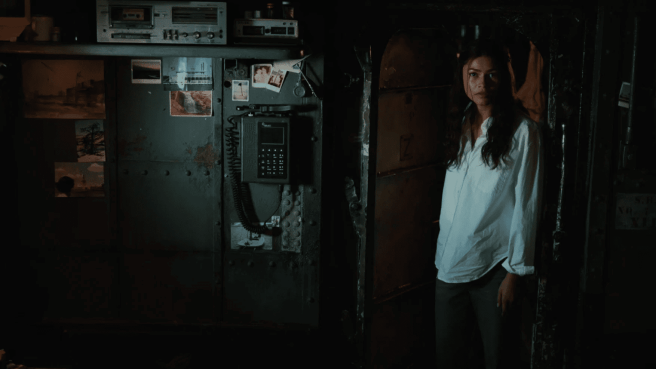 Zendaya as MJ in a white button-down shirt stands in a dimly lit, industrial-looking doorway in Spider-Man Brand New Day.
